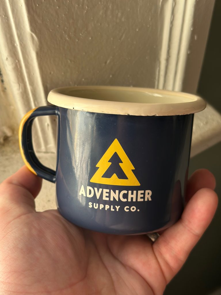 A blue and gold metal mug that reads "Advencher Supply Co." on the side.